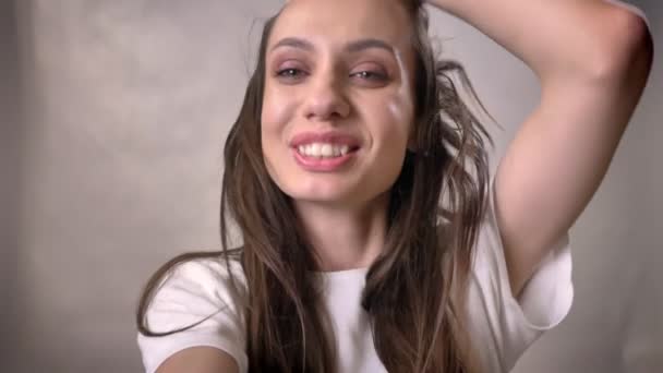 Jonge sexy brunette meisje speelt met haar, en houden van de camera, flirt concept, grijze achtergrond — Stockvideo