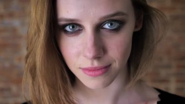 Dumanlı gözler ile genç çekici kız yüzünü kameraya gülümseyen, arka plan bulanık, izliyor