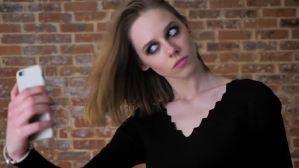 Junges sexy Mädchen mit rauchigen Augen macht Seifie auf ihrem Smartphone, Kommunikationskonzept, Backsteinhintergrund — Stockvideo