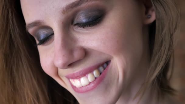 Tvář mladé okouzlující dívka s kouřově očima otevře oči a sleduje na fotoaparát, s úsměvem, snění koncept — Stock video