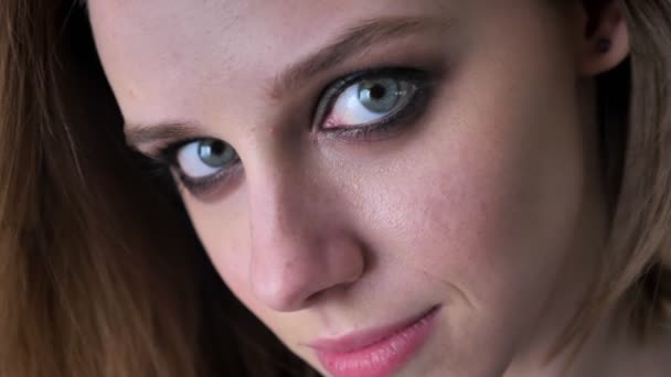 Rosto da menina encantadora jovem com olhos fumegantes está olhando para a câmera, fundo borrado — Vídeo de Stock