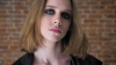 Dumanlı gözler ile genç seksi üzgün kız izlerken kamera, düşünme kavramı, tuğla arka plan