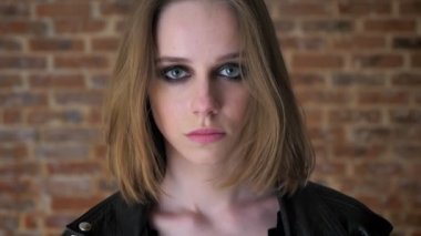 Dumanlı gözler ile genç seksi üzgün kız izlerken kamera, aşağı izlerken, düşünme kavramı, tuğla arka plan