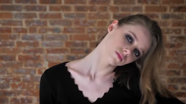 Молода секстет дівчина з димчастими очима грає з волоссям, концепцією флірту, цегляним фоном — стокове відео