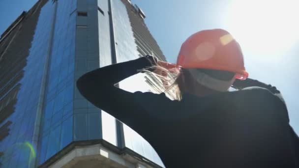 Mladá dívka tvůrce s hemlet se dívá na budování, ukazující velikost je délka dne v létě, budování koncepce, urbanistický koncept, pohled zespodu — Stock video