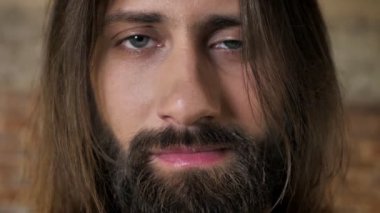 Sakallı genç güzel esmer adamın yüzünü kameraya, tuğla arka plan izliyor