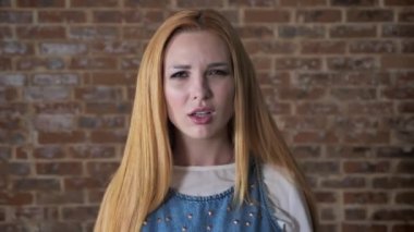 Genç havaya sarışın kız olduğunu kaybı, kameraya, izlerken tuğla arka plan