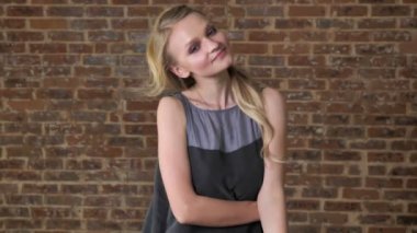 Genç Sevimli sarışın kız oynamaya saç, flört kavramı, tuğla arka plan