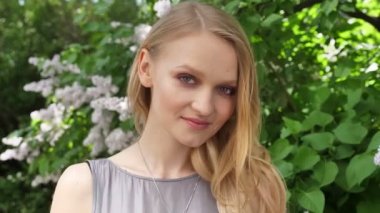 Genç çekici sarışın kız izlerken kamera parkta gündüzleri yaz, gülümseyen