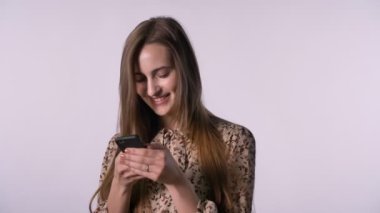 Genç mutlu kadın smartphone, iletişim kavramı, beyaz arka plan üzerinde mesaj okuyor