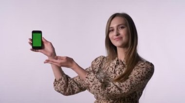 Genç güzel kadın Smartphone, işareti, kamera, iletişim kavramı, beyaz arka plan, saatler gibi yeşil ekran gösterir