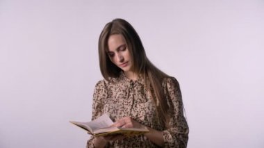 Genç güzel kadın kitap, kameraya, beyaz arka plan izlerken okuyor