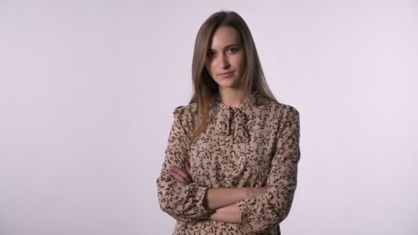 Junge hübsche Frau steht mit verschränkten Armen vor der Kamera, weißer Hintergrund — Stockvideo