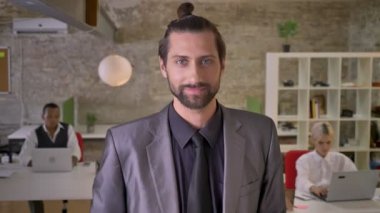 Sakallı çekici işadamı duruyor ve şampanya ofiste holding, meslektaşları çalışan dizüstü bilgisayarlar, şirket parti kavramı, iş kavramı ile