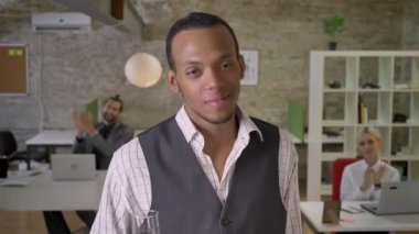 Genç Afrika işadamı duruyor ve şampanya gülümseyen, ofiste holding iş arkadaşları alkışlar, şirket parti kavramı, iş kavramı