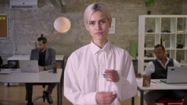 Güzel iş kadını ayakta ve ofis onun kollarında crossing, meslektaşları ile dizüstü bilgisayarlar, iş kavramı çalışıyoruz