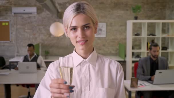 Ung vacker affärskvinna står och håller glas champagne i office, kolleger arbetar med bärbara datorer, företaget party konceptet, arbetskonceptet — Stockvideo