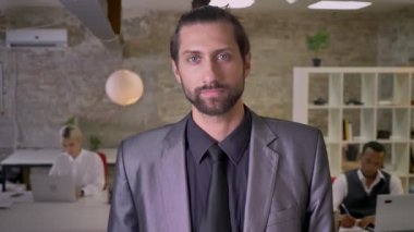 Sakallı yakışıklı işadamı ile geçti silah duruyor ve kamera Office izlerken, meslektaşları ile dizüstü bilgisayarlar, iş kavramı çalışıyoruz