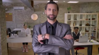 Sakallı yakışıklı işadamı ile geçti silah duruyor ve ofis, kameraya gülümseyen, izlerken meslektaşları ile dizüstü bilgisayarlar, iş kavramı çalışıyoruz