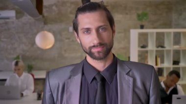 Sakallı yakışıklı emin işadamı izleyen kamera ofis, meslektaşları ile dizüstü bilgisayarlar, iş kavramı çalışan