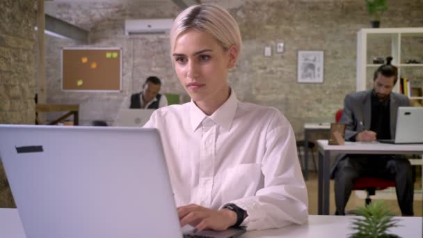 Joven mujer de negocios feliz está escribiendo en el ordenador portátil en la oficina, los colegas están trabajando en red con tecnologías, concepto de trabajo, concepto de comunicación — Vídeo de stock