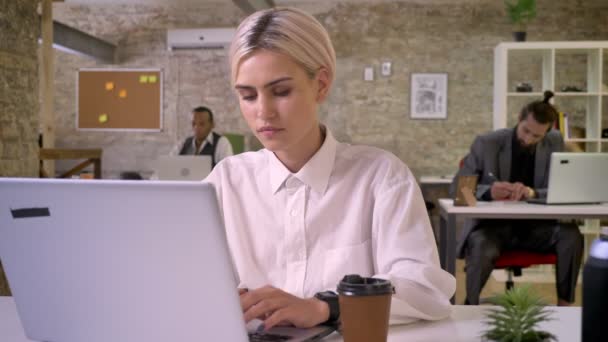 Jeune femme d'affaires heureuse dactylographier sur ordinateur portable au bureau, boire du café, collègues sont en réseau avec les technologies, concept de travail, concept de communication — Video