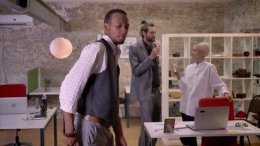 Serin Afrika işadamı ofiste dans ediyor, colleaues champange içme ve konuşurken, kavram, şirket parti konsept rahatla