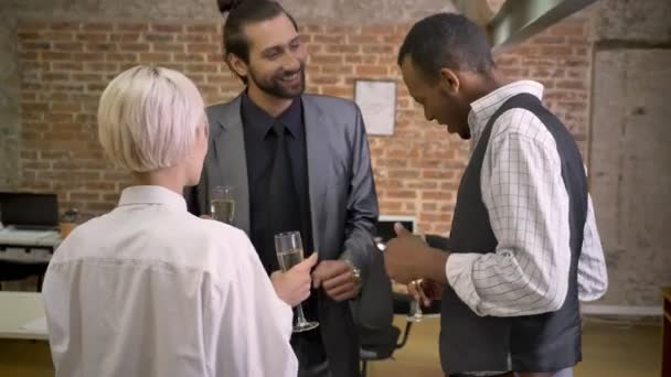 Три мультиэтнических работника танцуют в офисе, пьют шампанское, корпоративная вечеринка — стоковое видео
