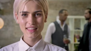 Genç güzel işkadını kamera ofis, izlerken gülümsüyor, meslektaşları konuşmak ve arka plan, iletişim kavramı, şirket parti conceptc şampanya içmek