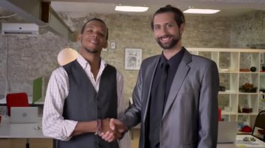 İki multy-etnik işçiler ofiste, kameraya, gülümseyen, iletişim kavramı izlerken elleri titriyor