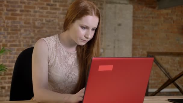 Молодая рыжая деловая женщина работает с ноутбуком в офисе, концепция работы, коммуникационная концепция — стоковое видео
