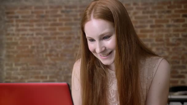 Τζίντζερ ωραία κοπέλα εργάζεται με το φορητό υπολογιστή στο γραφείο, ευτυχισμένο λόγω καλές ειδήσεις, έννοια εργασία, επιχειρηματική ιδέα, έννοια επικοινωνίας — Αρχείο Βίντεο