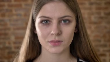 Genç Sevimli blonda çehresini izlerken kamera, düşünme kavramı, bulanık tuğla arka plan