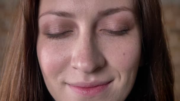 Лицо каштановых волос девушка открывает глаза, наблюдая за камерой, концепция сна, размытый фон — стоковое видео