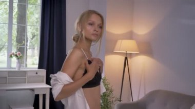 Genç seksi blonda Bayan iç çamaşırı duran ve vücudu ayna, önünde sutyen dokunmadan izlerken