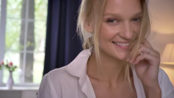 Молодая сексуальная блондинка в нижнем белье стоит в комнате, улыбаясь, флирт концепции — стоковое видео