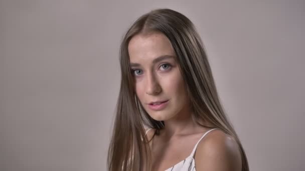 Jonge sexy meisje is bij camera kijken, aanraken van haren, verplaatsen, flirt concept, grijze achtergrond — Stockvideo