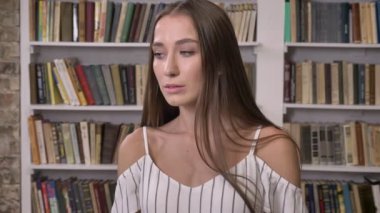 Genç çekici kız kameraya, izlerken gülümsüyor, flört kavramı, arka plan üzerinde Kütüphane