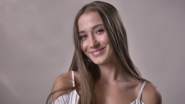Jonge sexy meisje is kijken op camera, verplaatsen, glimlachen, flirt concept, grijze achtergrond — Stockvideo