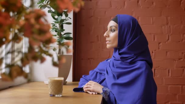 Kafa dönme ve kamera Cafe, deldi burunlu kadın oturuyor, gülümseyen hijab genç Müslüman kadın — Stok video