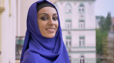 Kameraya bakarak ve gülümseyerek, sokakta duran hijab büyüleyici Müslüman kadında genç