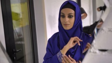 Aynada yansıması bakarak hijab kolye ve bilezik takı mağazasında çalışan genç Müslüman kadın