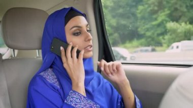 Arabada yolcu arka koltukta oturan ve cep telefonuyla konuşurken hijab genç Müslüman kadın