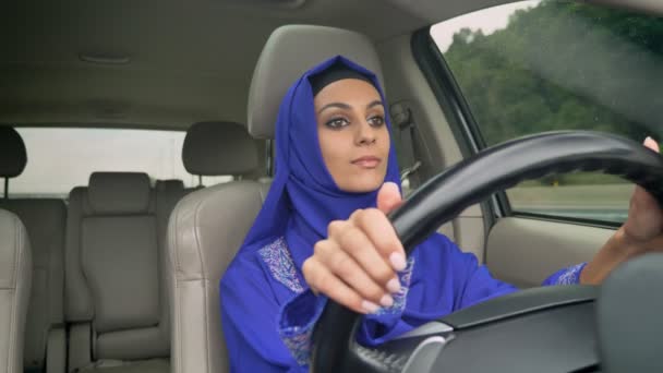 Jonge mooie Moslimvrouw in hijab besturen van een auto op de weg, glimlachend — Stockvideo