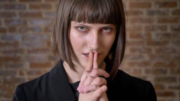 Ernstige jongedame hand in hand samen en kijken naar camera, geïsoleerd op baksteen achtergrond — Stockvideo