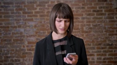 Genç hayal kırıklığı ifade, tuğla zemin üzerine izole ile telefon arayan kadın karışık