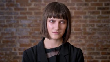 Tuğla duvara yakın duran ve kamera ve yana doğru genç kadın