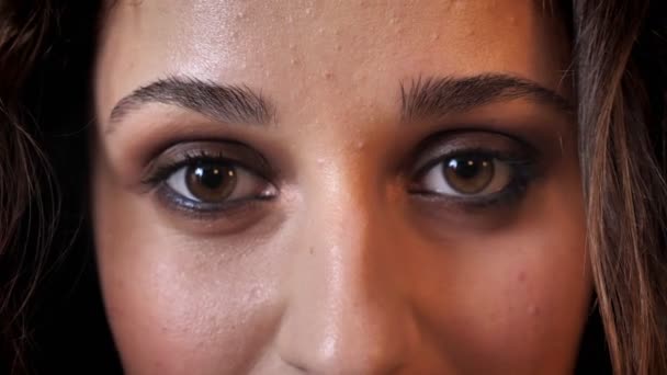 Olhos de mulher encantadora com cabelo escuro está sorrindo, assistindo a câmera, fundo de tijolo — Vídeo de Stock