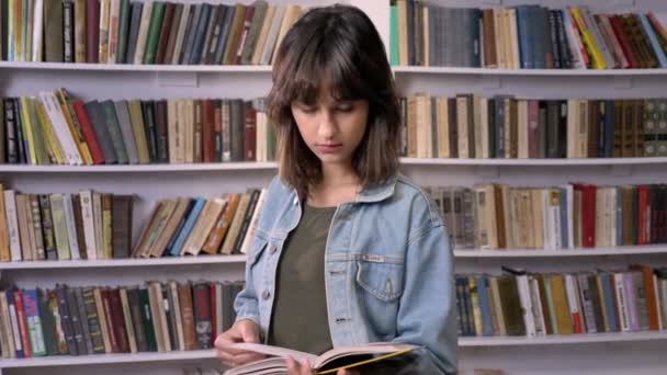 Девочка Брюнетка Печатает Книги Смотрит Камеру Читает Заднем Плане — стоковое видео