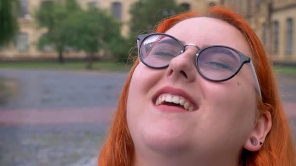 Menina gengibre gordo com óculos está andando no parque sob a chuva, assistindo no céu, conceito de inspiração — Vídeo de Stock